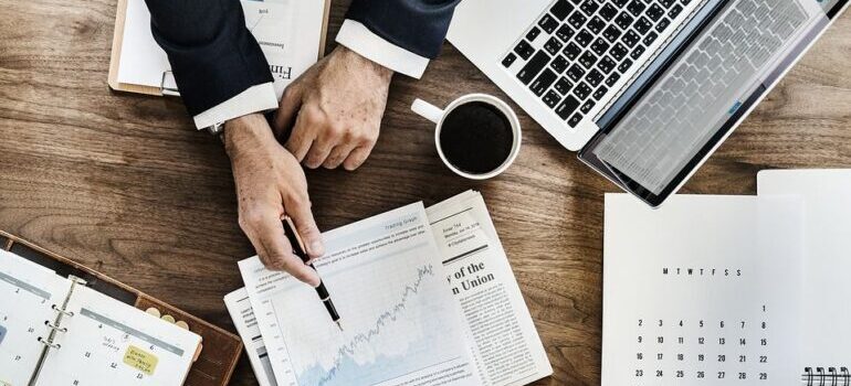 Desk filled with charts and analysis, with a man pointing to target the company hopes to achieve with email campaing.
