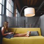 Girl sitting on a yellow office couch and working in the office.