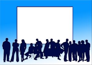 Group of employees in front of a large screen.