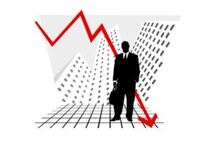 Businessman standing in front of a downward graph arrow.