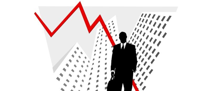 Businessman standing in front of a downward graph arrow.