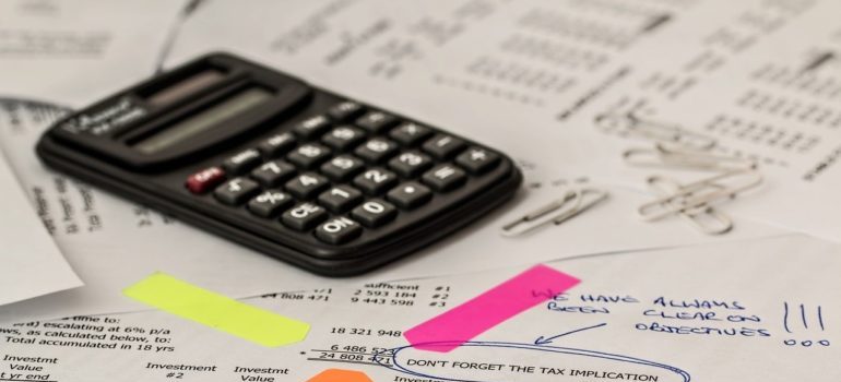 A pile of financial papers with a calculator and a pen.