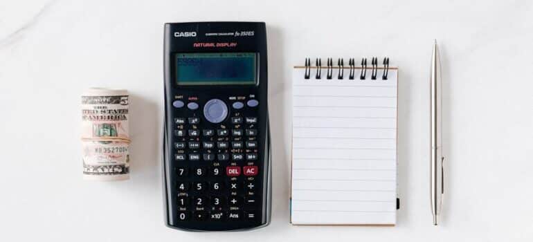 Roll of money, a calculator, notepad, and pencil