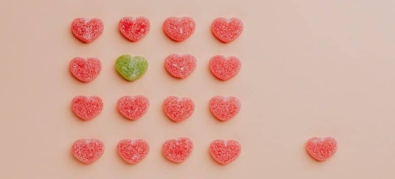A green heart in a group of pink hearts.