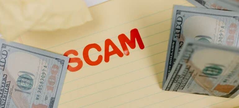 Word 'scam' in red letters with bills around it
