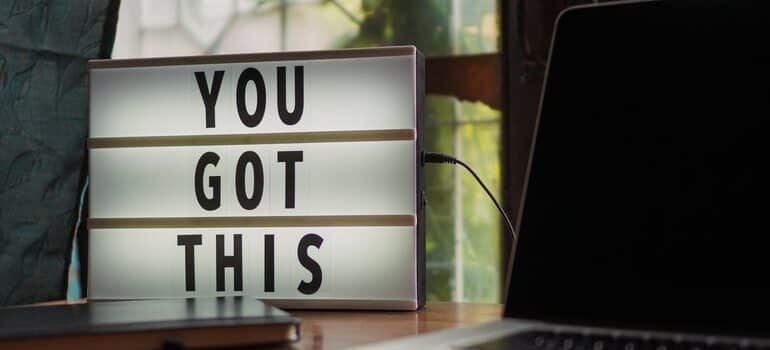 A lightbox sith the words "you got this" next to a laptop.