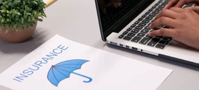 A paper with blue umbrella and insurance written on it next to a laptop