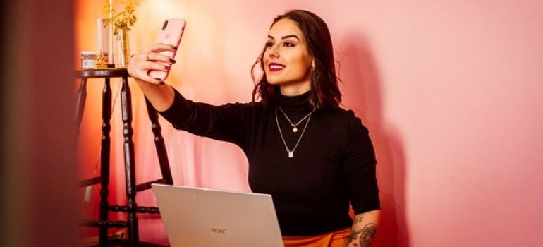 Social media influencer sitting on a couch and taking a selfie next to a lamp as an example of ways to generate leads n 2022