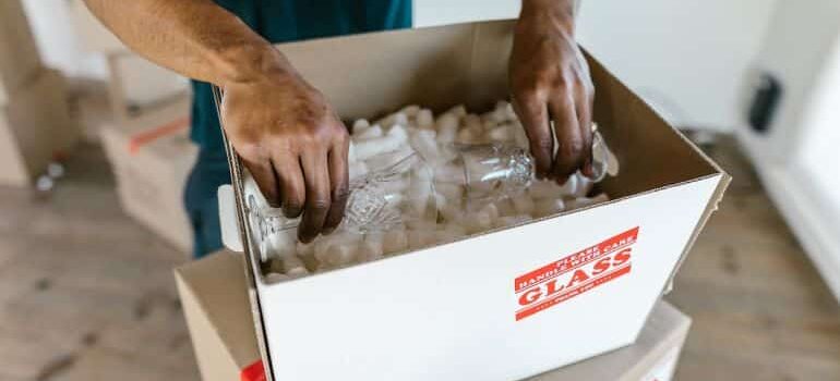 Member of moving crew packing glasses inside a box.
