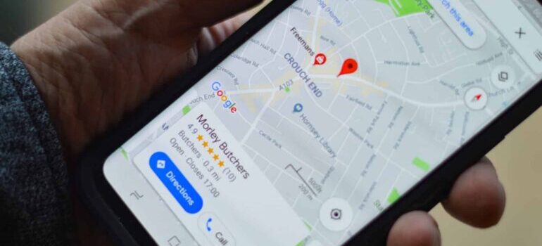 A person holding a phone and looking at a GMB profile through Google Maps