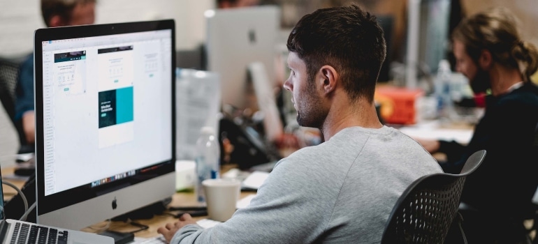Person sitting at a desktop computer and updating their GMB listing