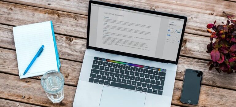 A blog post opened on a laptop that's situated on a desk next to a phone, a notebook, a pen, and a glass of water