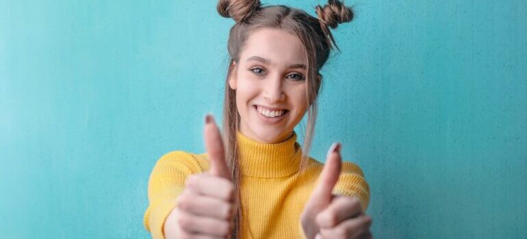 Woman holding thumbs up in front of a blue wall