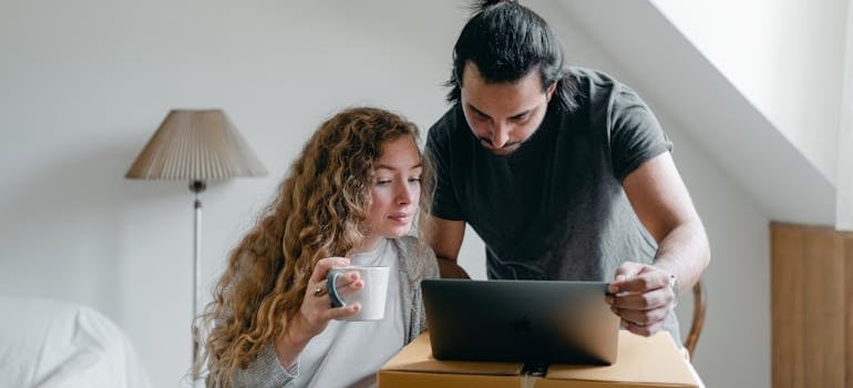 Two people using a laptop while preparing for moving
