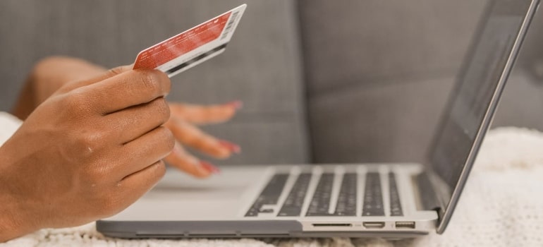 a person holding a credit card in front of computer