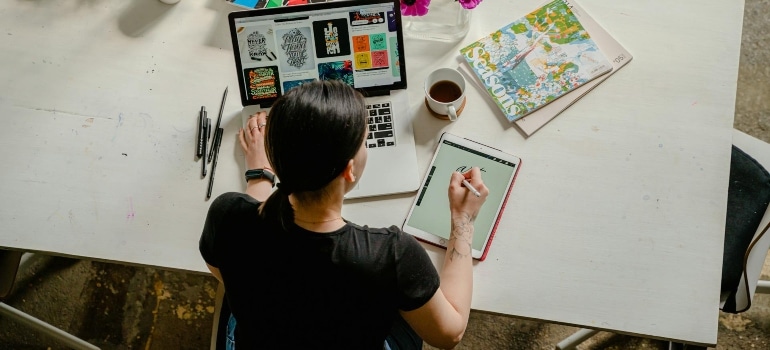 a woman doing some design on her tablet and laptop