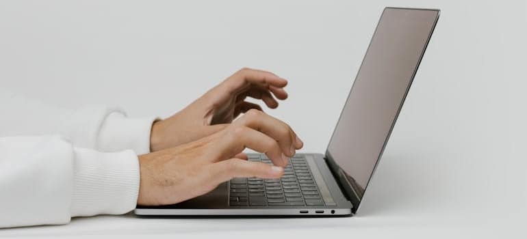 A person typing on a laptop to read about how to upsell moving services