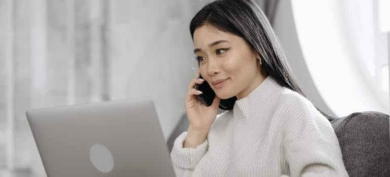 A satisfied person using their laptop while talking on the phone