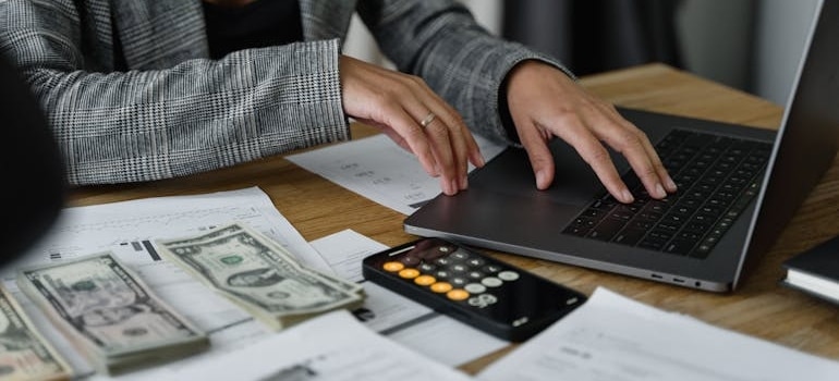 A person using a laptop and calculating costs