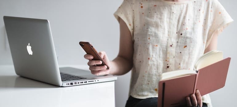 A person using a smartphone while holding a book