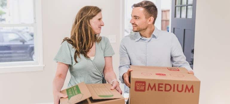 Two people carrying boxes while moving