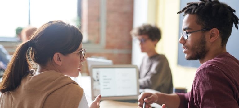 Two coworkers discussing the top 2025 digital marketing trends for moving companies
