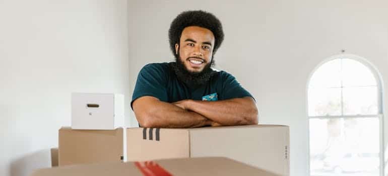 An employee of a moving company smiling and standing in front of boxes