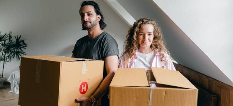 Two people carrying boxes while moving