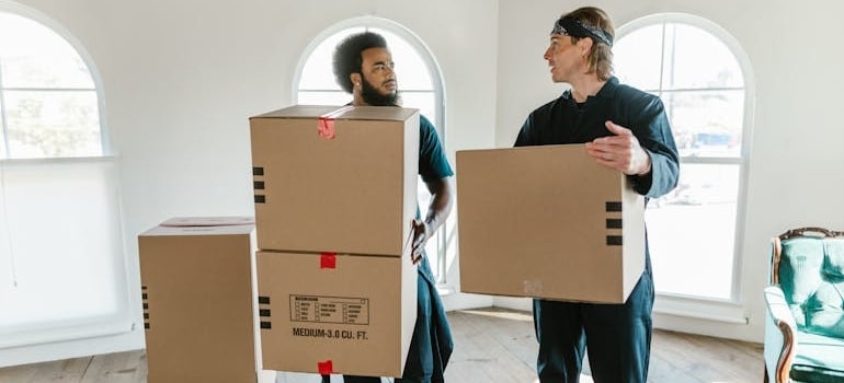 Two employees of a moving company holding boxes