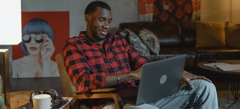 A smiling person sitting and exploring a website of a moving company