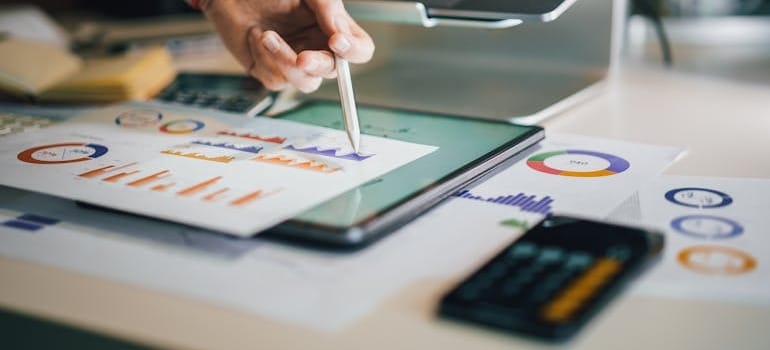 A business person analyzing charts to compare online vs offline marketing strategies for movers regarding cost
