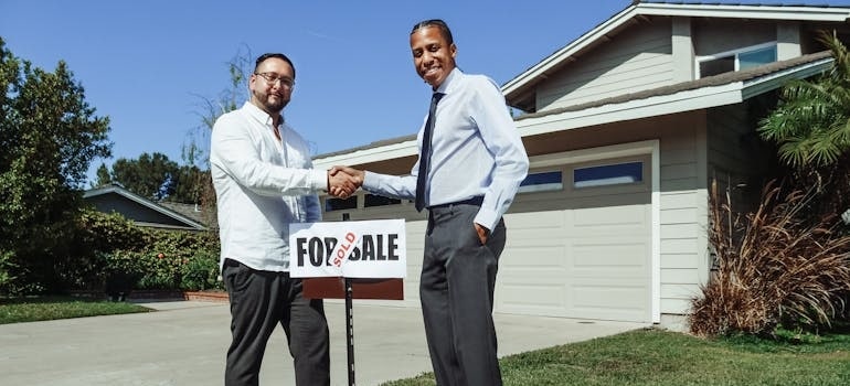 Two people shaking hands after reaching a home sale agreement