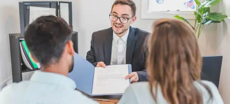 Real estate agent speaking with clients, an example of how to generate leads for a moving company through partnerships