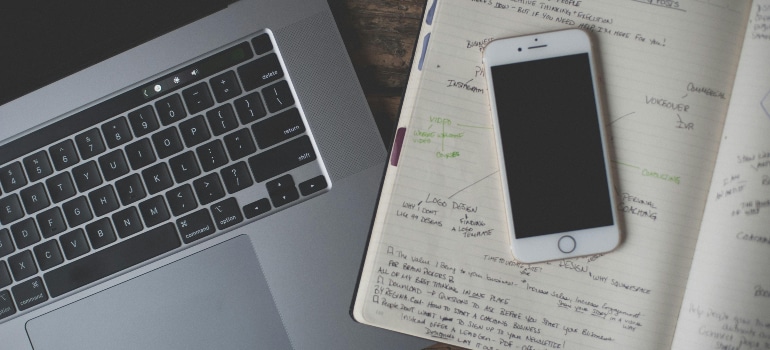 Laptop, notebook, and smartphone on a desk.