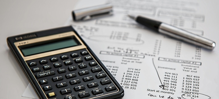 A calculator and paper showing cost calculations, representing the need to adjust marketing budgets for the DST.