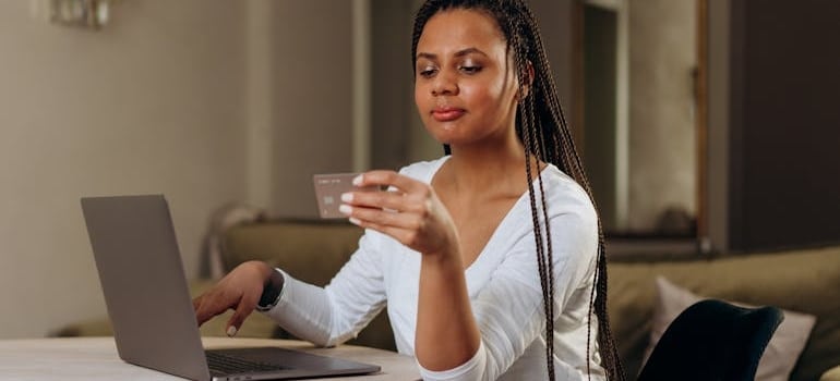 A person holding a credit card and paying for moving services online