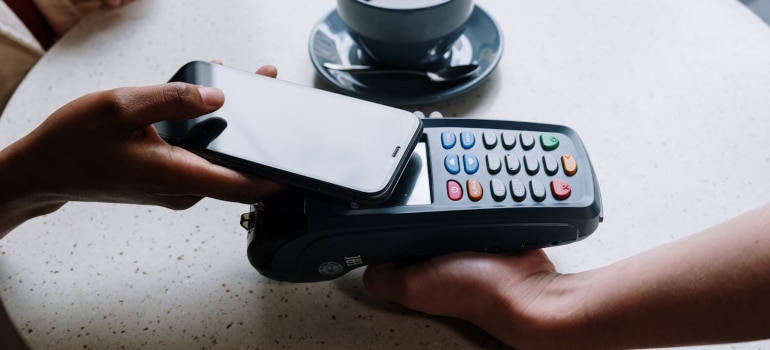 Customer using smartphone for contactless mobile payment at terminal