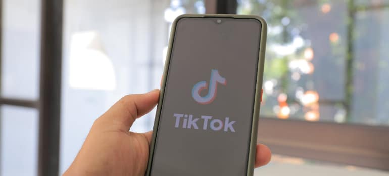Person holding a smartphone showing the TikTok app.