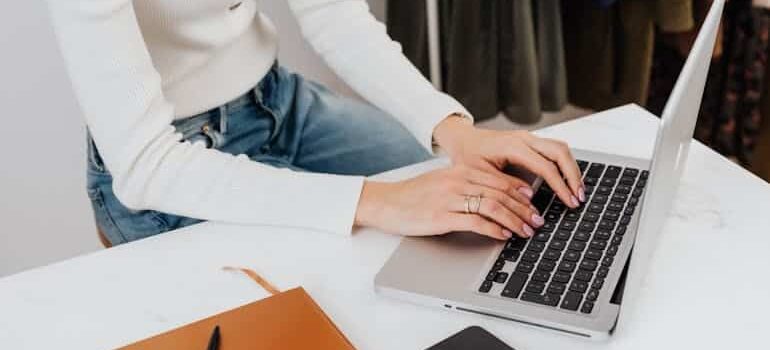A woman using a silver laptop to explore how AI helps movers write better emails quickly and professionally.