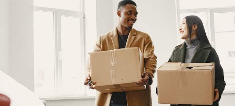 Two people carrying boxes during a move