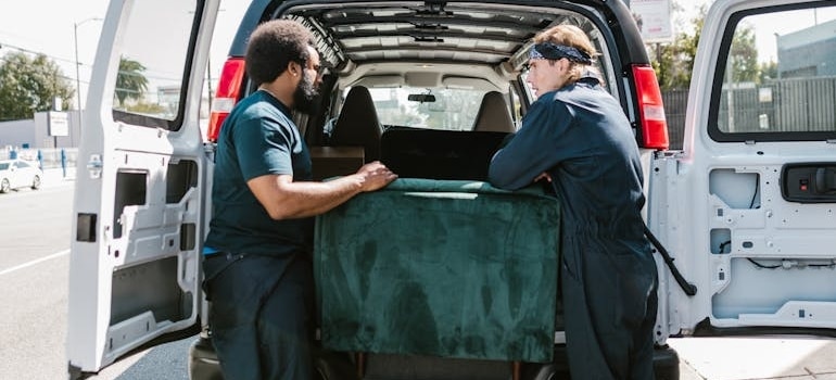 Two employees of a company loading a couch into a van