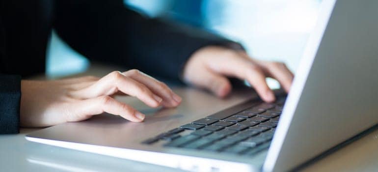 A person using a laptop to write and improve their company's SEO after learning how internal linking helps movers rank in more cities