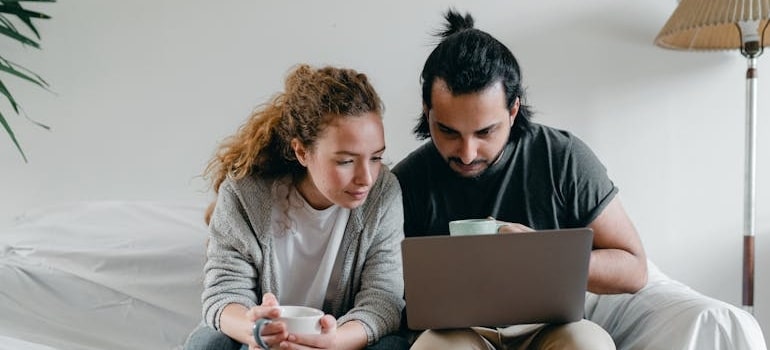 Two people using a laptop to search for movers on Google after packing boxes