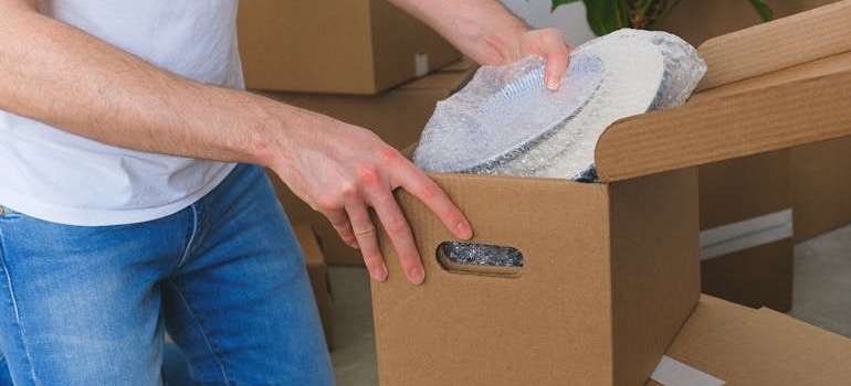 Person packing with cardboard boxes and plastic wrap, which is seen as a waste concern in Gen Z mover trends