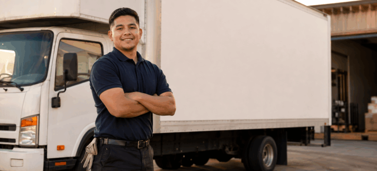 an employee smiling next to a branded moving truck.